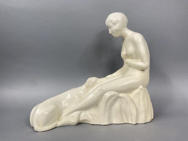 Sujet en céramique craquelée beige représentant une femme assise avec un chien…