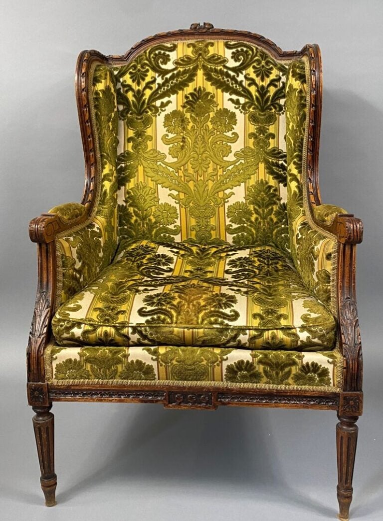 Une bergère à oreilles en bois mouluré et sculpté, pieds fuselés et cannelés, a…