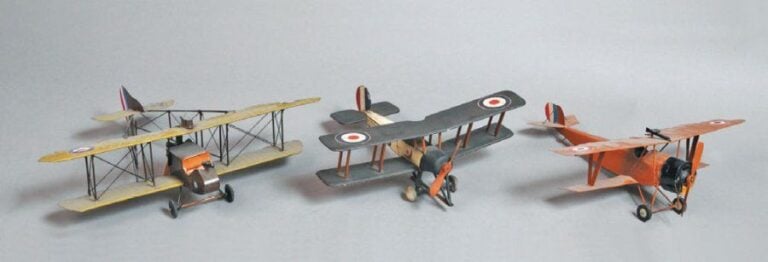 (a, b, c) Maquette moderne artisanale d'un biplan en tôle peinte, L 24 x E 26 cm + maquette moderne d'un avion « de Havilland » en tôle peinte, L 26 x E 31 cm + « Avro 504 » modèle ancien artisanal en bois peint, L 22 x E 23 cm, 70%