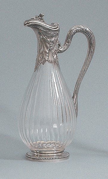 Aiguière ovoïde en cristal cannelé ; les pieds, anse et encolure en argent à décor de feuilles d'acanthe, fleurs et perle