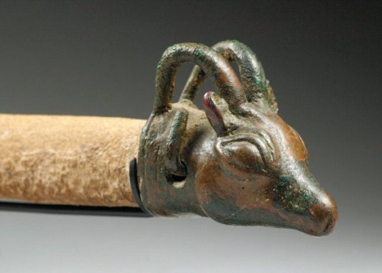 AIGUISOIR AU BOUQUETIN Aiguisoir en pierre au manche en bronze en forme de tête de bouquetin aux cornes hémicirculaire