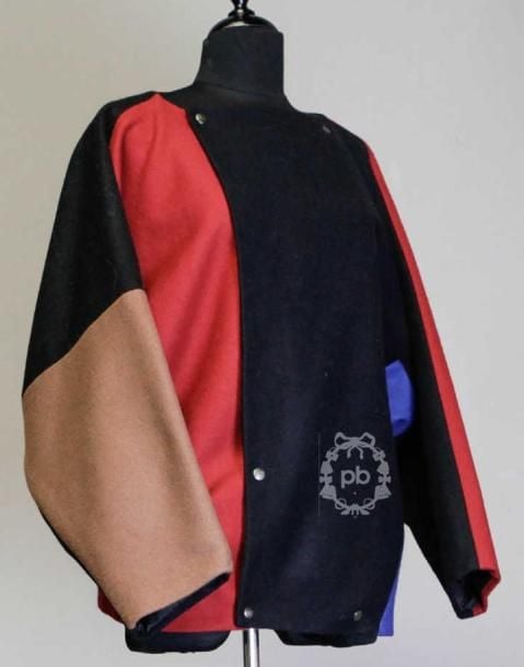Ample VESTE légèrement entravée composée d'empiècements en lainage noir, rouge et bleu dur, encolure carrée sur double boutonnage pressions, manches chauve-souris, deux poches dans les coutures (env TS/M)