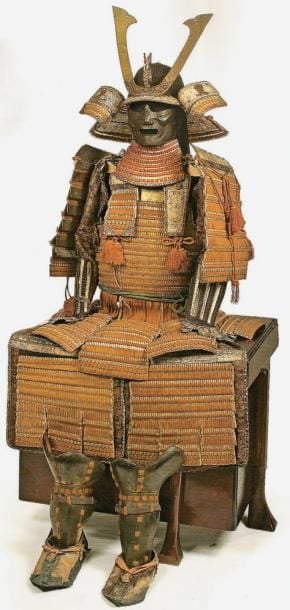 Armure de type domaru, composée d'un kabuto en fer de patine noir, à lamelles et rivets proéminents, le maedate en bois doré représentant un dragon, le shikoro terminé par de larges fukigaeshi revêtus de cuir; le mempo en fer patiné noir, avec yodarekake à cinq plaques et lacets orange; la cuirasse (Do) en deux parties, se fixant sur le côté, les plaques laquées or réunies par des lacets orangés, tout comme jupe, sous jupe, et épaulières (kusazuri, haidate et osode