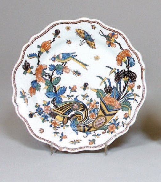 Assiette à bord contourné, décor polychrome de cornes d'abondance ornées d'oeillets noirs, d'oiseaux branchés et papillon