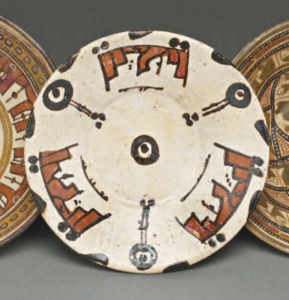 ASSIETTE AUX « FLEURS » ET INSCRIPTIONS Assiette à large marli, décorée en rouge et brun sur engobe blanc de « fleurs » discoïdes et de trois inscription