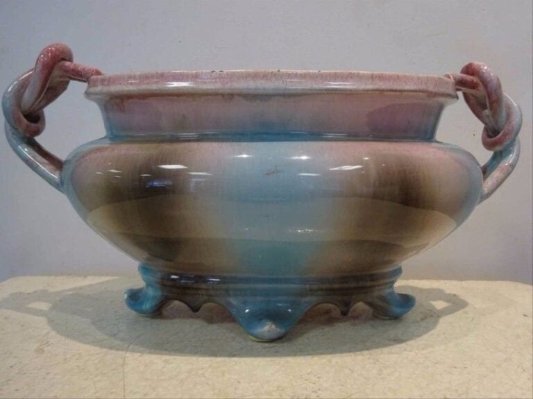 Attribué à Delphin MASSIER Jardinière oblongue et quadripode à anses torsadées et tressées en faïence polychromée bleu, rose et bru