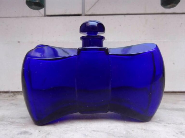 BACCARAT Flacon à parfum et son bouchon en cristal pressé-moulé teinté bleu nuit en forme de noeud de papillon stylis