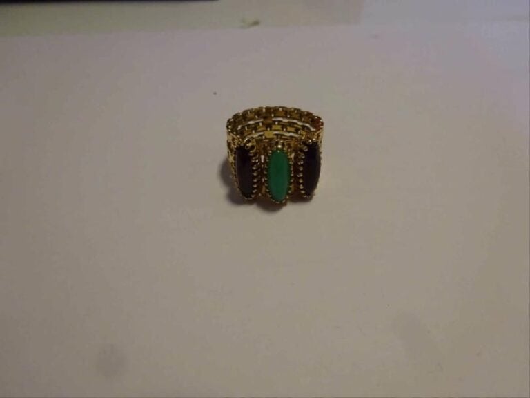 Bague bandeau ajourée formée de trois brins, rehaussée de cabochons de pierres rouges synthétiques et d'un cabochon de calcédoine teint