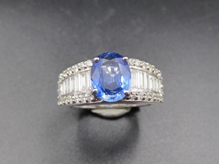 BAGUE «bandeau» en or gris (750 millièmes) serti d'un saphir de CEYLAN de forme ovale pesant 2,29 carats, épaulé de diamants baguettes et taille brillan