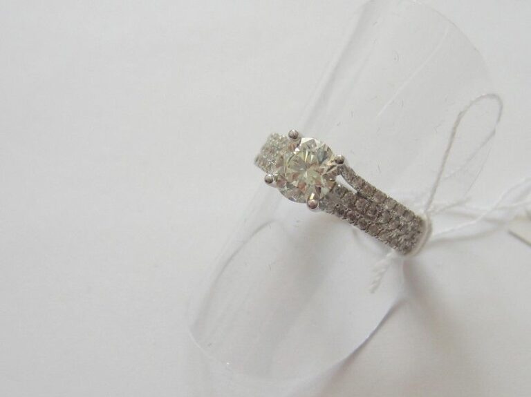 BAGUE «bandeau» en or gris (750 millièmes) serti de trois lignes de diamants rehaussées d'un diamant taille brillant pesant 0,8 cara