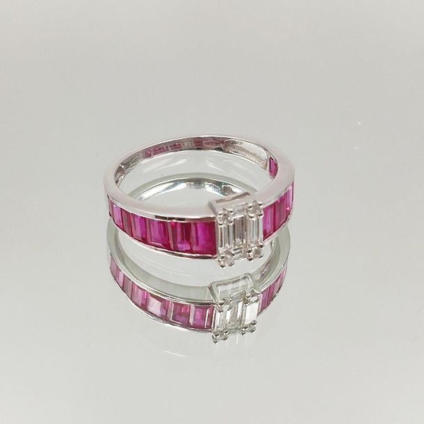 •BAGUE bandeau or gris (750‰) centré de diamants taille brillant et baguette, épaulé de rubis calibrés, en chut