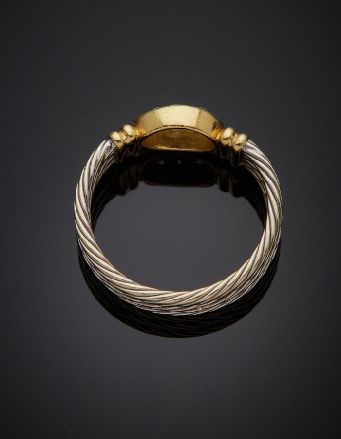BAGUE "câble" en or jaune et or gris (750‰) godronné, le centre pavé de dix dia…