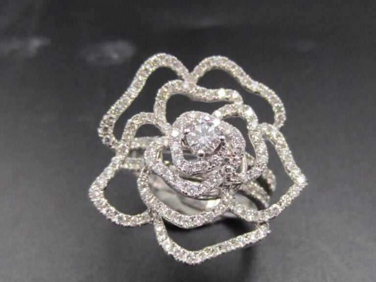 BAGUE «camélia» en or gris (750 millièmes) ajouré, serti de diamants taille brillant dont un, au centre, plus importan