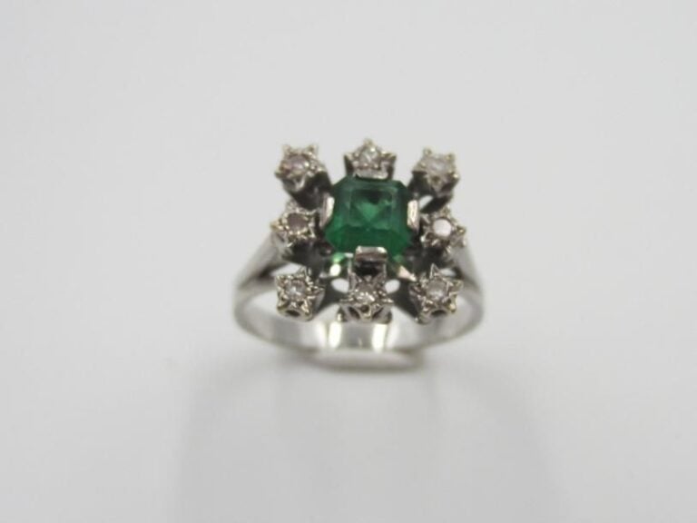 BAGUE carrée en or gris (750 millièmes) ajouré serti d'une émeraude taillée à degrés entourée de diamants 8/