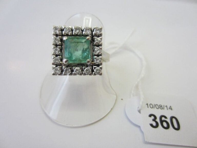 BAGUE carrée en or gris (750 millièmes) serti d'une émeraude taillée à degrés entourée de diamants taille brillan