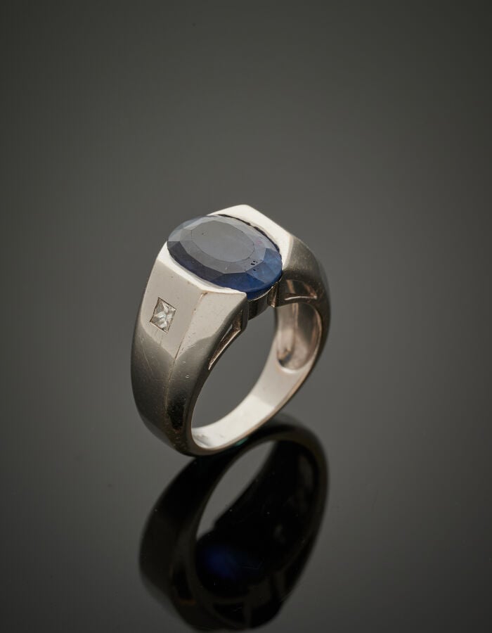 BAGUE chevalière en or gris (750‰) serti d'un important saphir ovale épaulé de…
