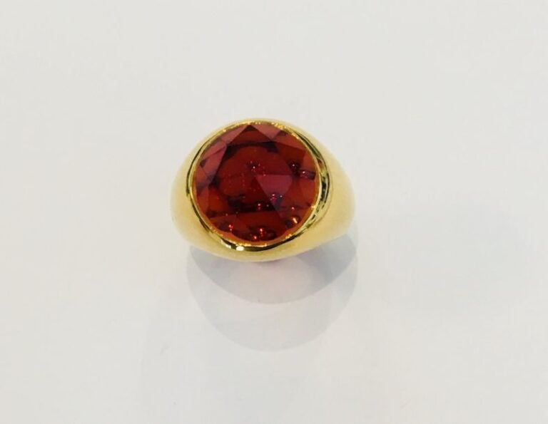 BAGUE chevalière en or jaune (750 millièmes) surmonté d'un grenat spessartite facetté de forme rond