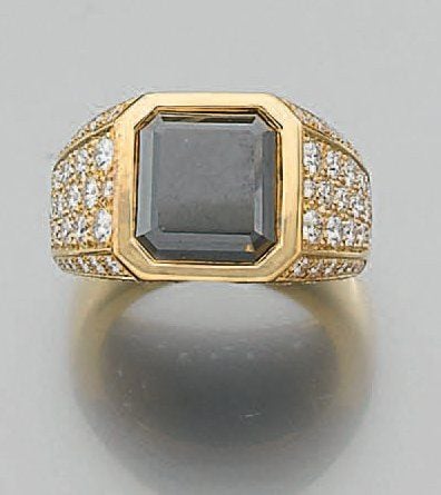 BAGUE chevalière en or jaune serti d'un diamant noir taillé à degrés, épaulé de pavages de diamants taille brillan