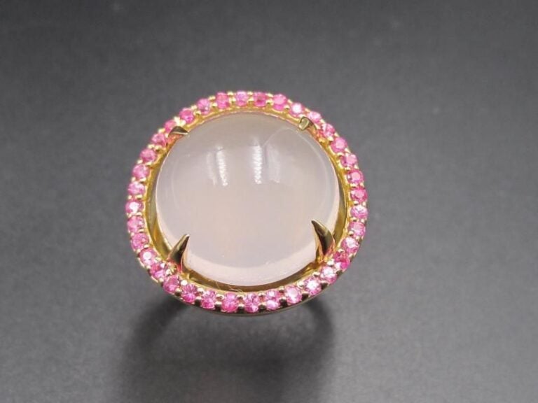 BAGUE circulaire en vermeil (925 millièmes) serti d’un quartz rose cabochon entouré de saphirs ros