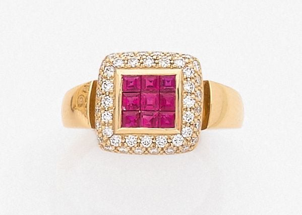 •BAGUE «coussin» en or jaune (750‰) centrée de neuf rubis calibrés en serti invisible, entourés de diamants taille brillan