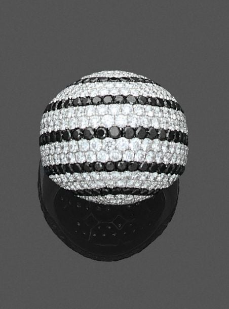 •BAGUE «dôme» en or gris (750‰) pavé d'alignements de diamants taille brillant blancs et noirs alterné