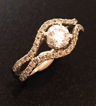 BAGUE en or gris (750 millièmes) ajouré à motifs de lignes sinueuses serti de diamants taille brillant dont un au centre plus importan
