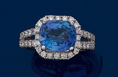 BAGUE en or gris (750 millièmes) ajouré serti d'un saphir de forme coussin, pesant 4,40 carats, entouré et épaulé de lignes de diamants taille brillan