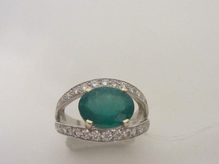BAGUE en or gris (750 millièmes) ajouré serti d'une émeraude de forme ovale, pesant 2,29 carats, soulignée de deux lignes de diamants taille brillan