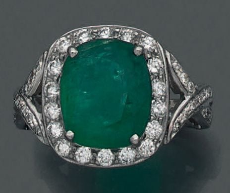 BAGUE en or gris (750 millièmes) ajouré serti d'une émeraude, pesant 5 carats, de forme coussin entourée et épaulée de diamants taille brillan
