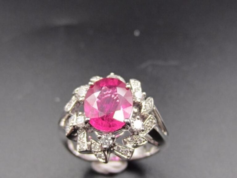 BAGUE en or gris (750 millièmes) ajouré serti d’un saphir rose pesant 2,5 carats de forme ovale, entouré de diamants taille brillant, à motifs rayonnan