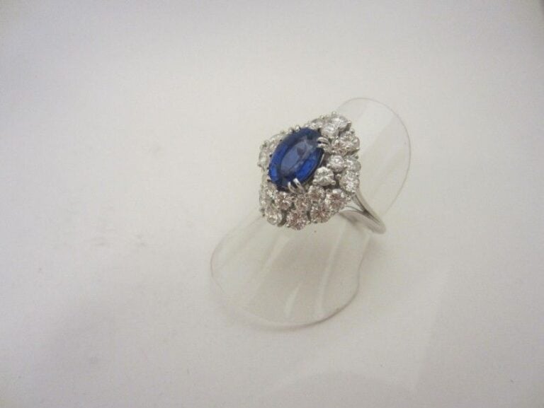 BAGUE en or gris (750 millièmes) légèrement juponné serti d’un saphir de forme ovale dans un double entourage de diamants