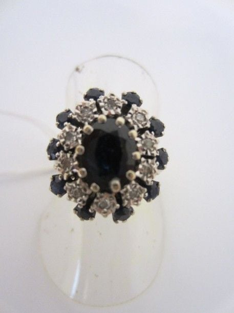 BAGUE en or gris (750 millièmes) ornée d'un saphir ovale dans un double entourage de saphirs et diamant