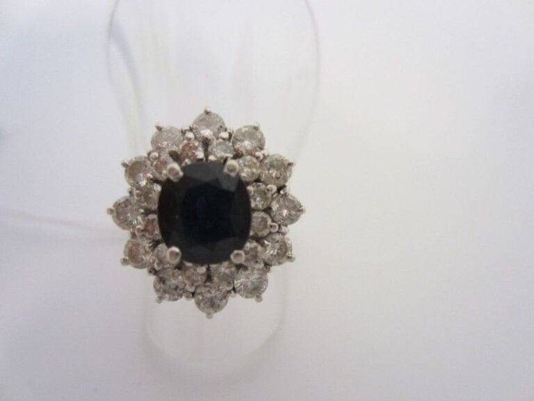 BAGUE en or gris (750 millièmes), ornée d'un saphir ovale dans un double entourage de diamants taille brillan