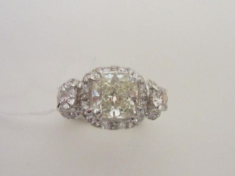 BAGUE en or gris (750 millièmes) serti d'un diamant taille coussin épaulé et entouré de diamants taille brillant dont deux plus importan