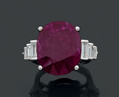BAGUE en or gris (750 millièmes) serti d'un important rubis pesant 18,27 carats épaulé de six diamants baguettes en chut