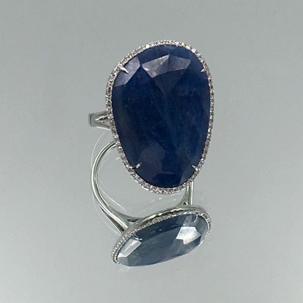 BAGUE en or gris (750 millièmes) serti d'un important saphir facetté entouré de diamants taille brillan