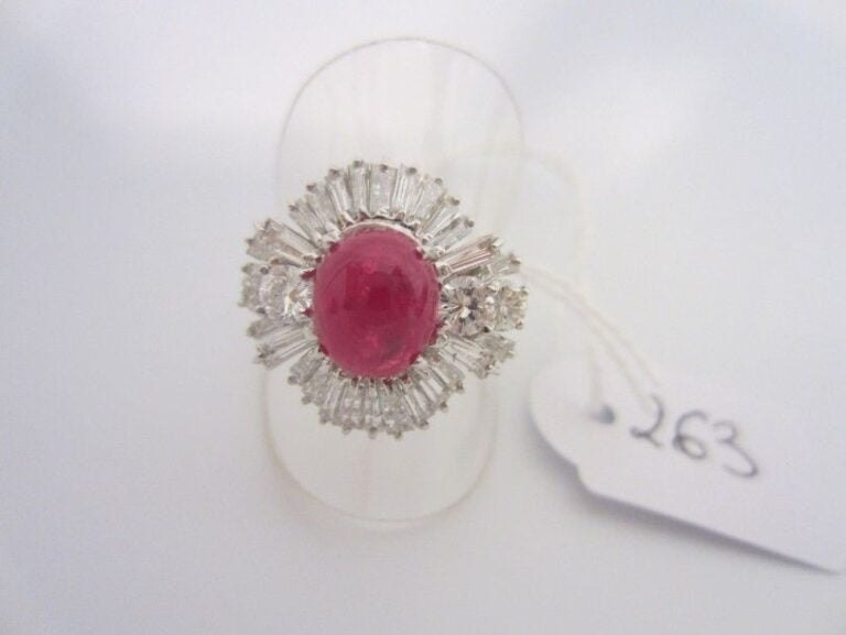 BAGUE en or gris (750 millièmes) serti d'un rubis cabochon épaulé de diamants taille brillant et baguett