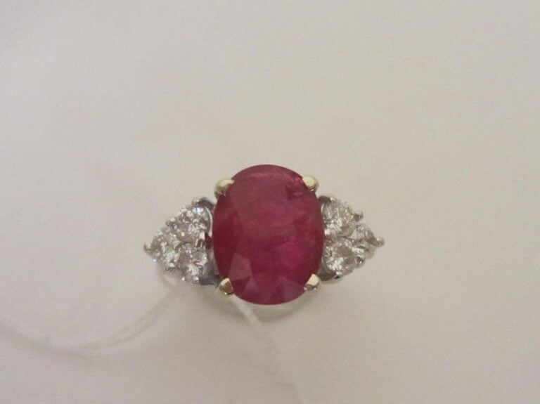 BAGUE en or gris (750 millièmes) serti d'un rubis de forme ovale pesant 5,04 carats, épaulé de six diamants taille brillan