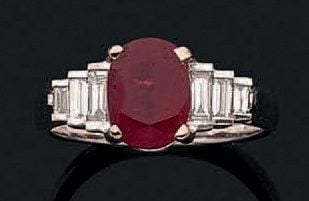 BAGUE en or gris (750 millièmes) serti d'un rubis ovale pesant 2,37 carats épaulé de trois diamants baguettes de chaque côté, en chut