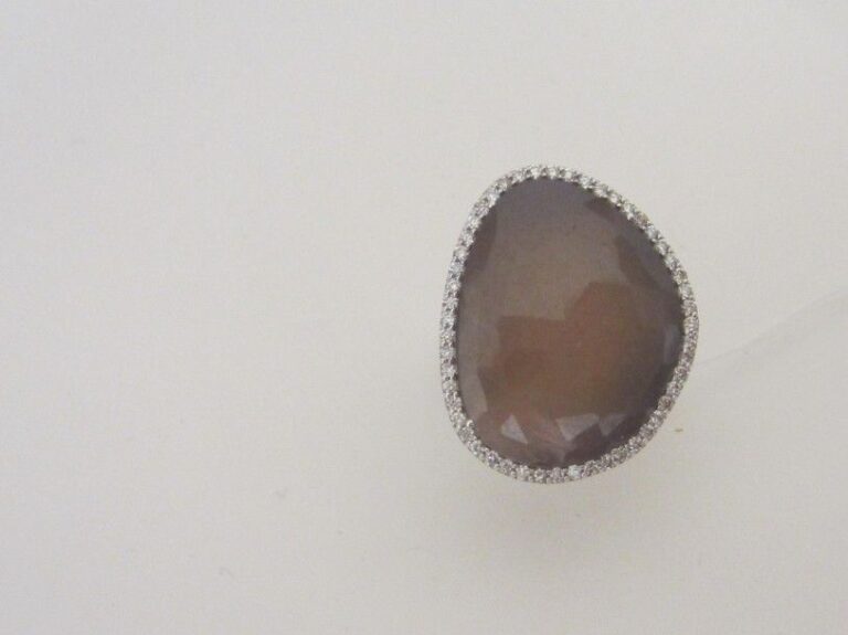 BAGUE en or gris (750 millièmes) serti d'un saphir brun opaque facetté, entouré d'une ligne de diamants taille brillan