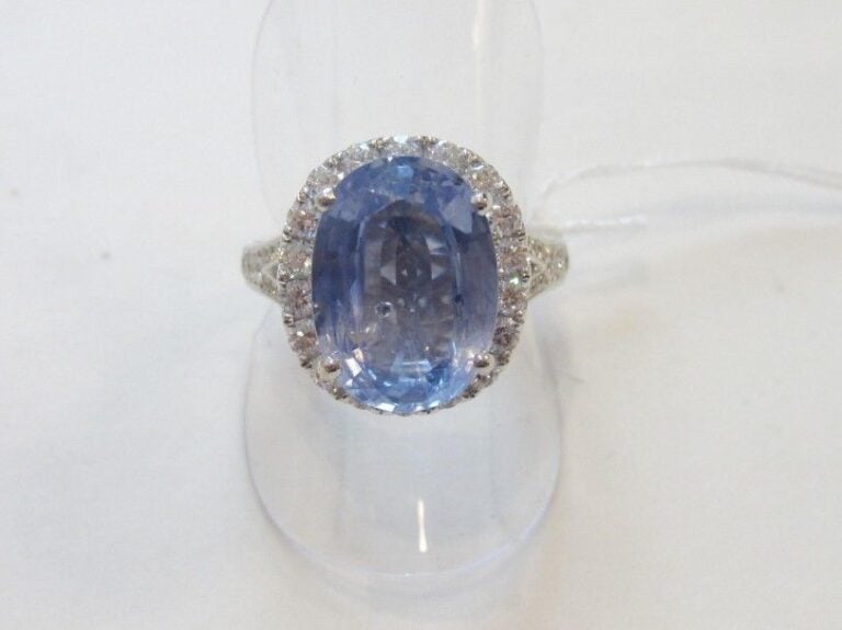 BAGUE en or gris (750 millièmes) serti d'un saphir ovale de couleur claire entouré et épaulé de diamants taille brillan