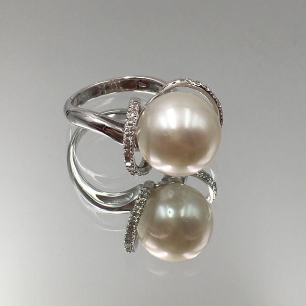 BAGUE en or gris (750 millièmes) serti d'une perle de culture blanche, épaulé de deux anneaux pavés de diamants taille brillan