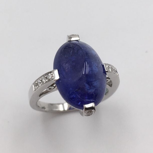 BAGUE en or gris (750 millièmes) serti d'une tanzanite ovale taillée en pain de sucre, épaulée de diamants taille brillan
