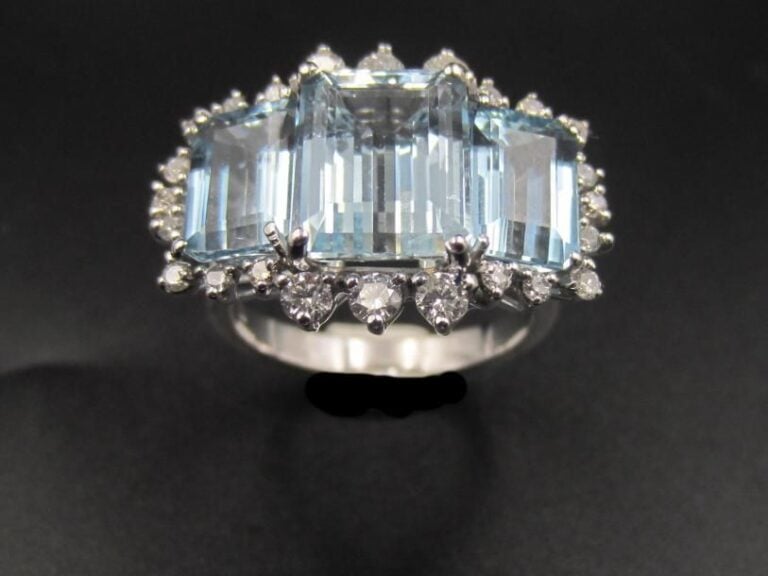 BAGUE en or gris (750 millièmes) serti de trois aigues-marines de forme rectangulaire taillées à degrés, entourées de diamants taille brillan