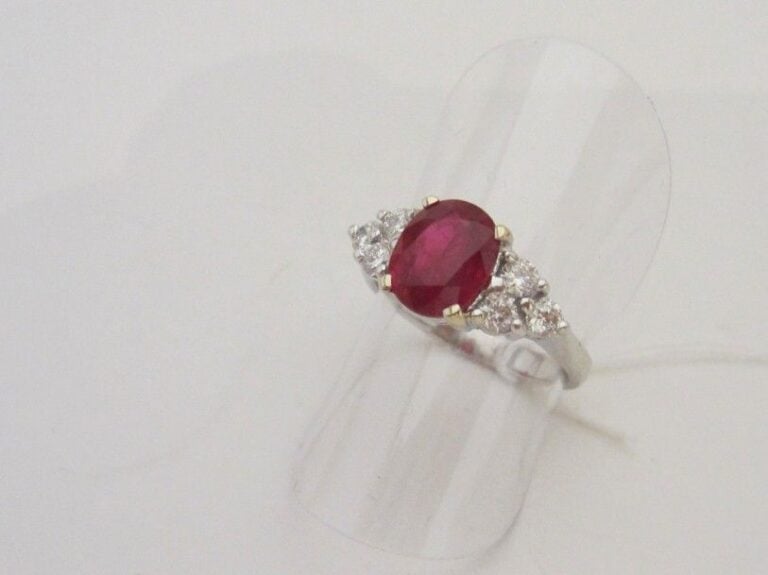 BAGUE en or gris (750 millièmes) serti d’un rubis de forme ovale, pesant 2,10 carats, épaulé de six diamants taille brillan