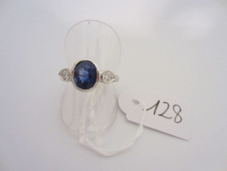 BAGUE en or gris (750 millièmes) serti d?un saphir de forme ovale épaulé de deux diamants taille brillant en serti clo