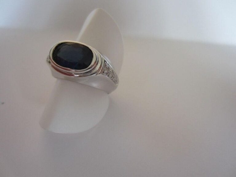 BAGUE en or gris (750 millièmes) serti d?un saphir de forme ovale épaulé de deux pavages de diamants taille brillan