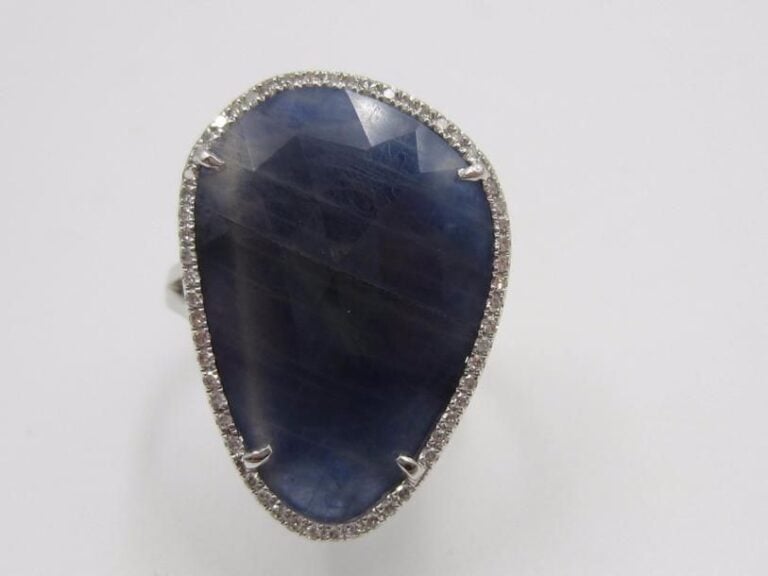 BAGUE en or gris (750 millièmes) serti d’un saphir plat et facetté, entouré de diamants taille brillan