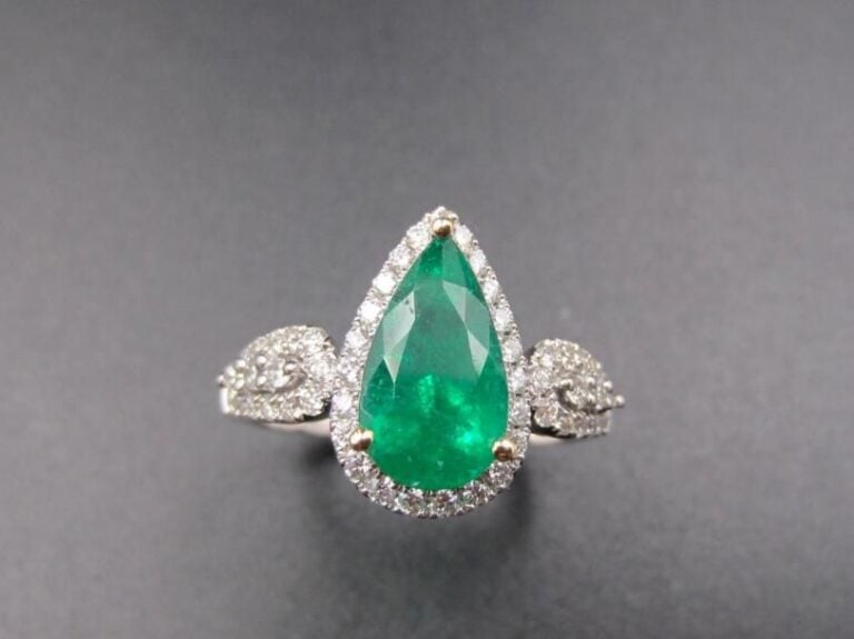 BAGUE en or gris (750 millièmes) serti d’une émeraude de forme poire entourée et épaulée de diamants taille brillant             Doigt : 54        Poids brut : 4,1 g