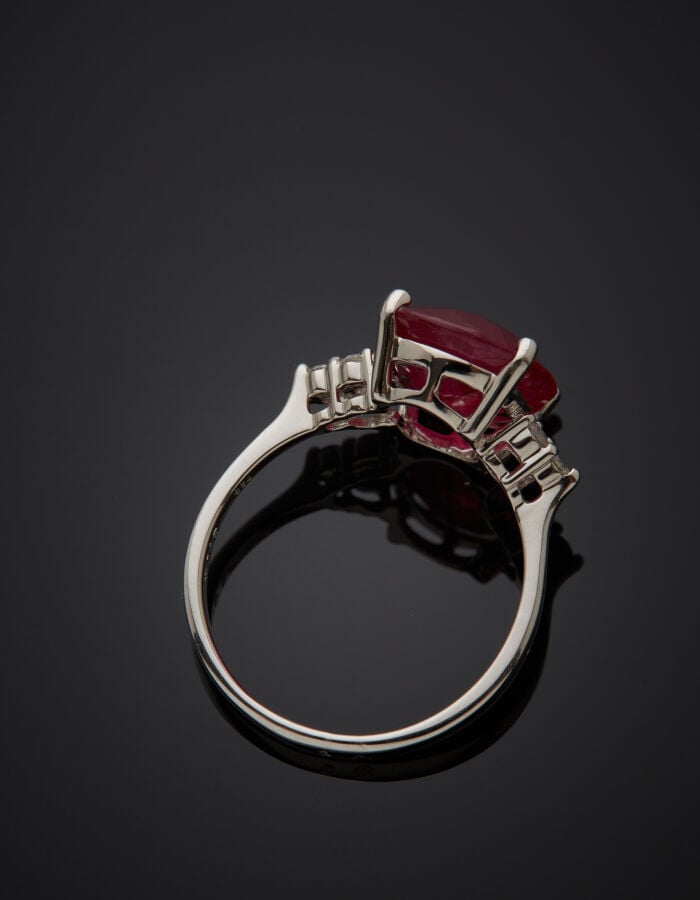 BAGUE en or gris (750‰) serti d'un rubis de forme ovale, épaulé de trois diaman…